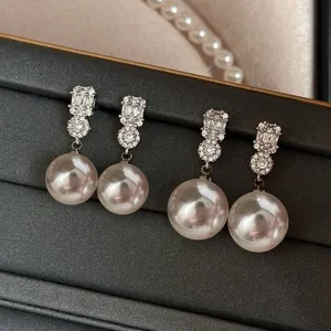 Elegant French-style pearl drop earrings with sparkling crystals displayed in a jewelry box