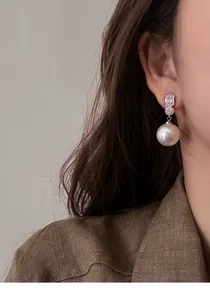 Close-up of a model wearing elegant French style pearl drop earrings with sparkling crystals