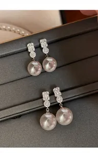 Macro detail of elegant pearl pendant earrings with sparkling zirconia stones