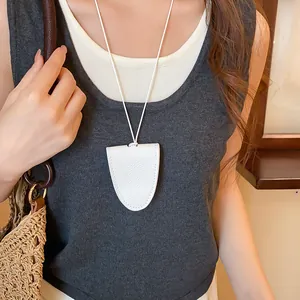 Detailopname van witte lederen brillenhouder ketting gedragen bij casual outfit.