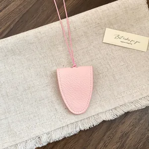 Detail van roze lederen brilhouder hanger met getextureerde afwerking en koord
