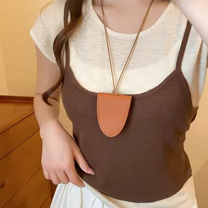 Detailopname van een bruine leren brilhouder hangketting op een stijlvolle outfit