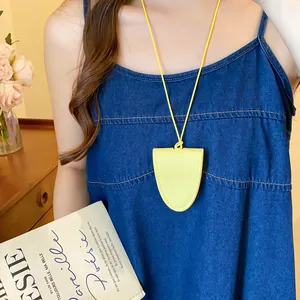 Detailweergave van een felgele leren brilhouder ketting op een blauwe denim jurk.