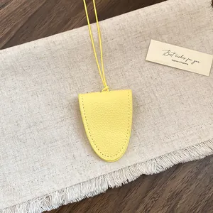 Detailweergave van een heldergele leren brillenhouder hanger op een linnen achtergrond