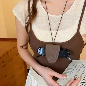 Detail van een bruine lederen brillenhouder ketting gedragen over een bruine tanktop