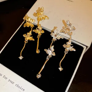 Gedetailleerd overzicht van elegante goud- en zilveren vlinderoorbellen met fonkelende kristallen.