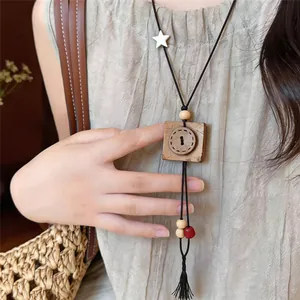 Detail view of retro wooden square pendant necklace with tassel and star charm.