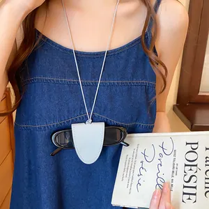 Detail van draagbare lederen zonnebrilhouder ketting gedragen op een denim jurk