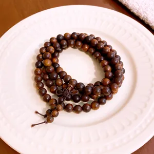 Detailed macro view of a dark wooden bead multi-strand bracelet on a white plate