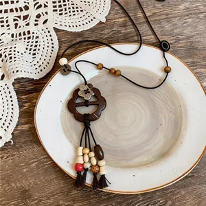 Close-up of a vintage New Chinese style wooden flower pendant necklace on a ceramic plate
