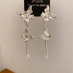 Gedetailleerde close-up van zilverkleurige vlinder oorbellen met glanzende strass accenten.