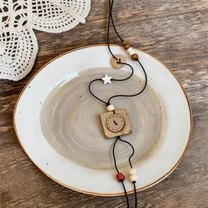 Macro detail of retro wooden square pendant necklace displayed on a rustic ceramic plate