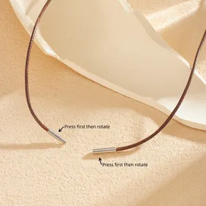 Detailopname van de metalen druk-en-draaisluiting op een bruine leren koordketting.