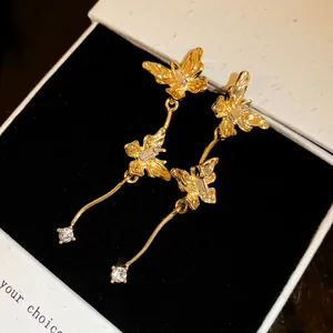 Detailopname van gouden vlinder oorbellen met fonkelende kristallen in een geschenkdoosje