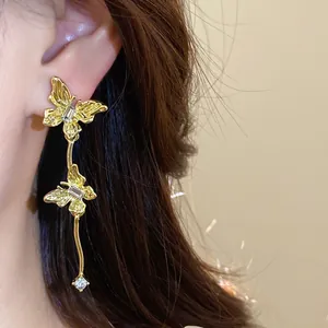 Detailopname van gouden vlinder kwastjes oorbellen met fonkelende strass steentjes