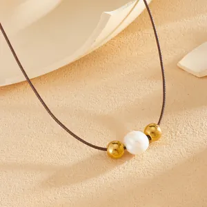 Detailopname van een minimalistische ketting met een parel en vergulde stalen kralen op koord.