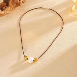 Detailopname van een boheemse parelketting met vergulde kralen op een bruin koord