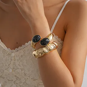 Vue détaillée d'un bracelet doré martelé vintage et d'un bracelet en résine au poignet