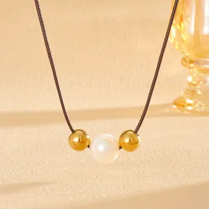 Macro detail van natuurlijke zoetwaterparel en gouden kralen aan een bruine koordketting