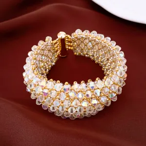 Detailaufnahme eines schimmernden Perlenarmbands mit Goldakzenten auf brauner Seide.