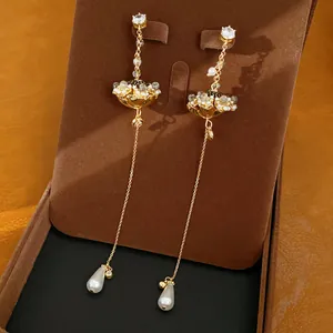 Detailweergave van gouden bloemoorbellen met zirkoon en elegante parelhangers