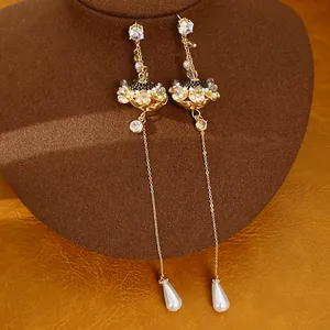 Detailopname van elegante vintage oorbellen met zirkoonbloemen en pareldruppels op een display.