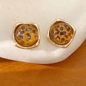 Nahaufnahme von Vintage-Ohrsteckern aus Leoparden-Harz mit goldenen Rahmen.