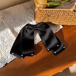 Pince à cheveux élégante avec nœud en tissu noir et strass brillants en gros plan