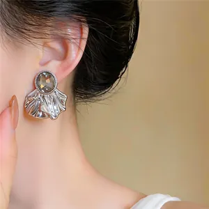 Detail view of elegant silver shell stud earrings featuring a smoky oval rhinestone