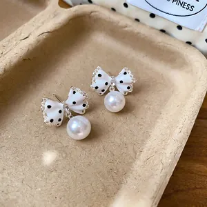 Gedetailleerde opname van zoete polkadot strik oorbellen met elegante witte parels.