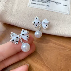 Detailopname van schattige gestippelde strikoorbellen met elegante witte parels.