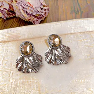 Detailed view of silver oval earrings with amber stone and shell-like metal base
