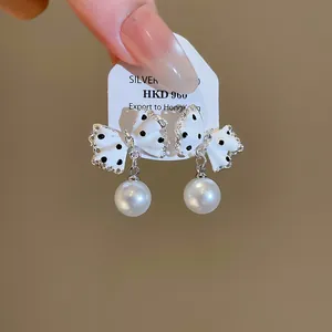 Gedetailleerde weergave van witte strikoorbellen met stippen en elegante ronde hangparels