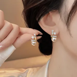 Detailed view of elegant 14k gold-plated star and pearl stud earrings on a model.