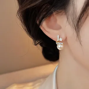 Detail shot of 14k gold plated zircon star earring with elegant hanging pearl