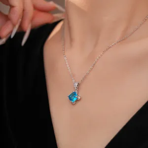 Detailansicht einer silbernen Halskette mit blauem Zirkon-Anhänger an einem Model