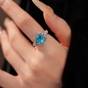 Makroansicht eines blauen Zirkonrings mit gedrehtem Pavee-Band an einem Finger