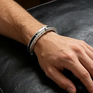 Detailaufnahme eines industriellen Niet-Armreifs aus Edelstahl an einem männlichen Handgelenk