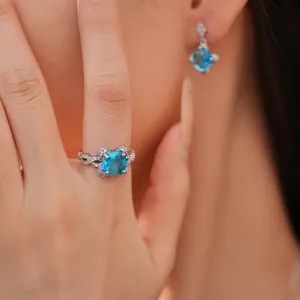 Detaillierte Nahaufnahme eines eleganten blauen Zirkonia-Ring- und Ohrring-Sets an einem Modell