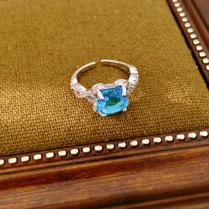 Nahaufnahme eines silbernen Rings mit blauem Zirkon auf strukturiertem braunem Stoff