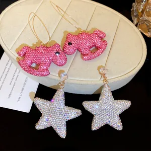 Detailed view of sparkling rhinestone hippo and star drop earrings with silver needles