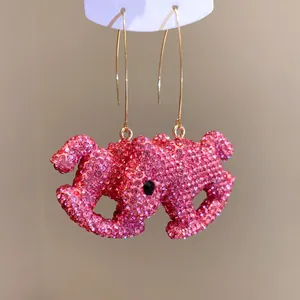 Detailed view of pink rhinestone-encrusted elephant earrings with gold-tone hooks