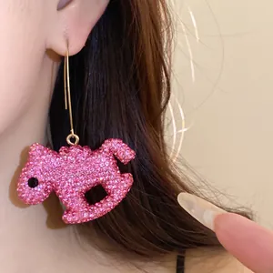 Detailed shot of a pink sparkling horse pendant earring encrusted with rhinestones
