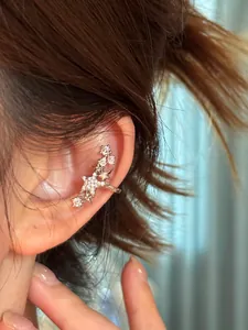 Détail d'un ear cuff étoile en argent avec des zircons étincelants sur l'oreille du modèle