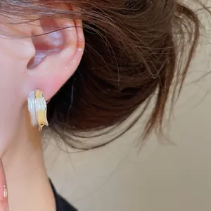 Detailansicht unregelmäßiger gewellter C-Ohrringe in Gold- und Silberoptik