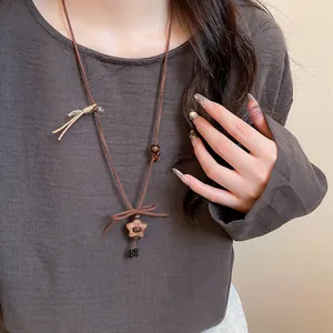 Close-up of wooden bear and star pendant necklace on model's brown sweater