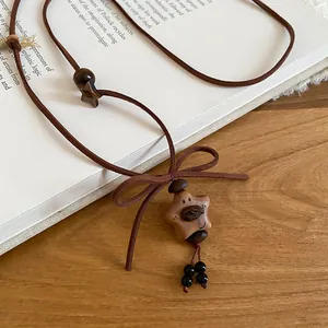 Detail view of a retro wooden star necklace featuring a bear face and a brown bow