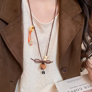 Detail view of a retro bear pendant necklace with wooden beads on a brown jacket