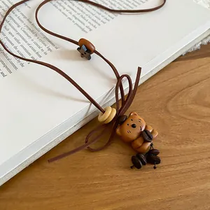 Close-up of a vintage wooden bear and star pendant on a brown cord necklace.