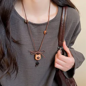 Close-up of a vintage wooden bear pendant necklace with a brown cord bow